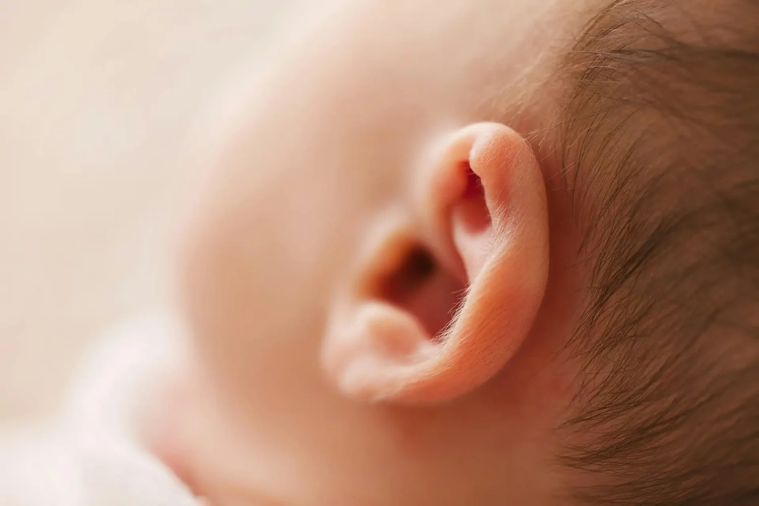 Gentle close-up of a newborn baby's ear, showcasing delicate features in a soft focus image