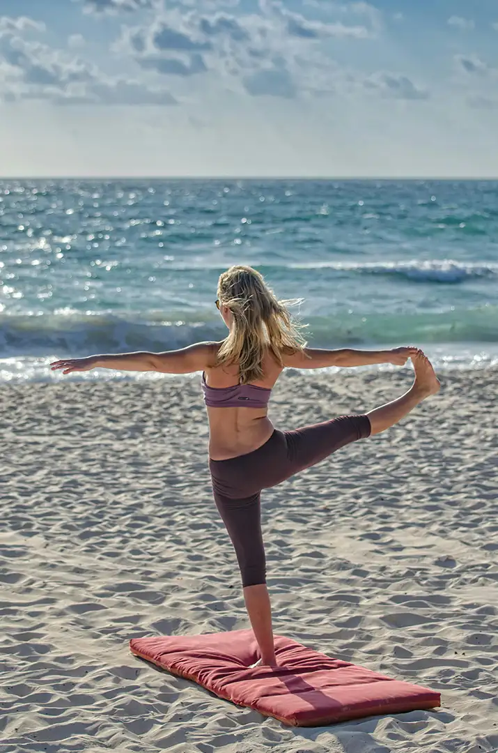 Woman balancing and doing yoga on the beach