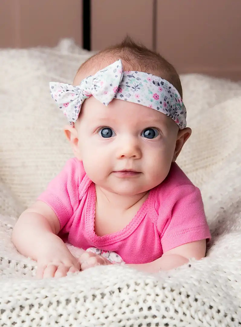 Infant girl laying on blanket looking at camera