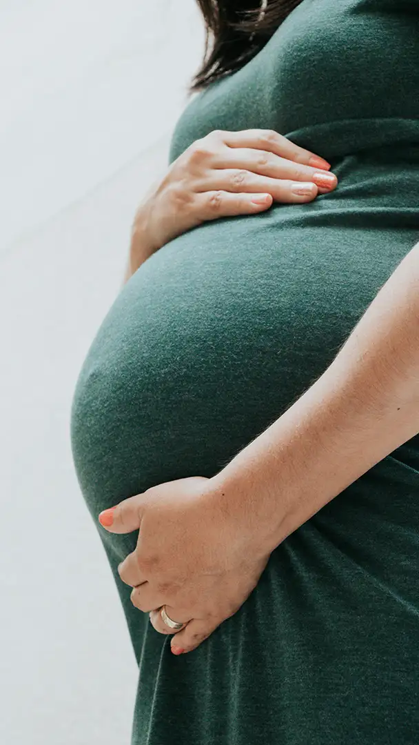 Pregnant woman gently cradling belly