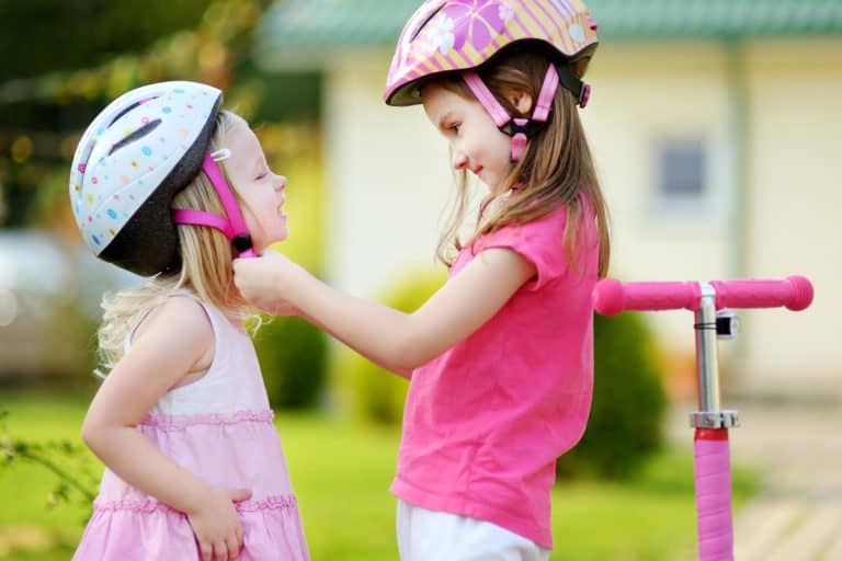 Two girls fitting their bike helmets