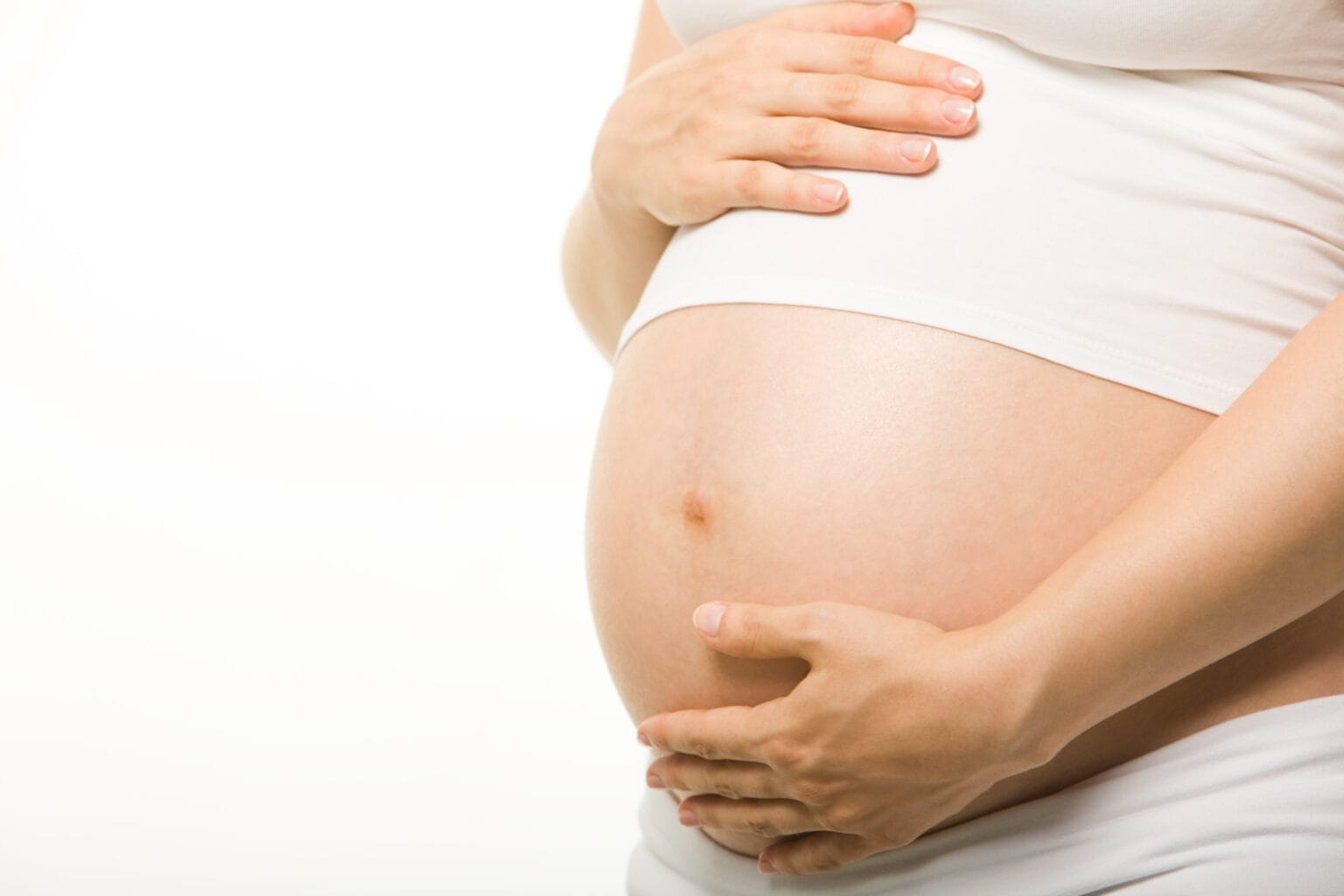 Pregnant woman gently holding stomach.