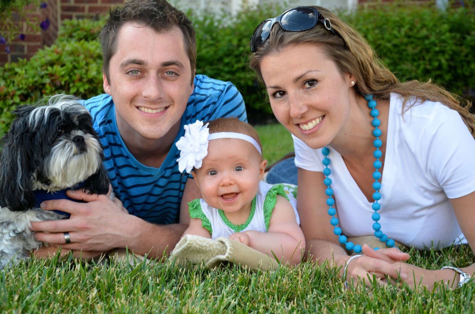 Happy family (mom, dad, and toddler) laying on grass