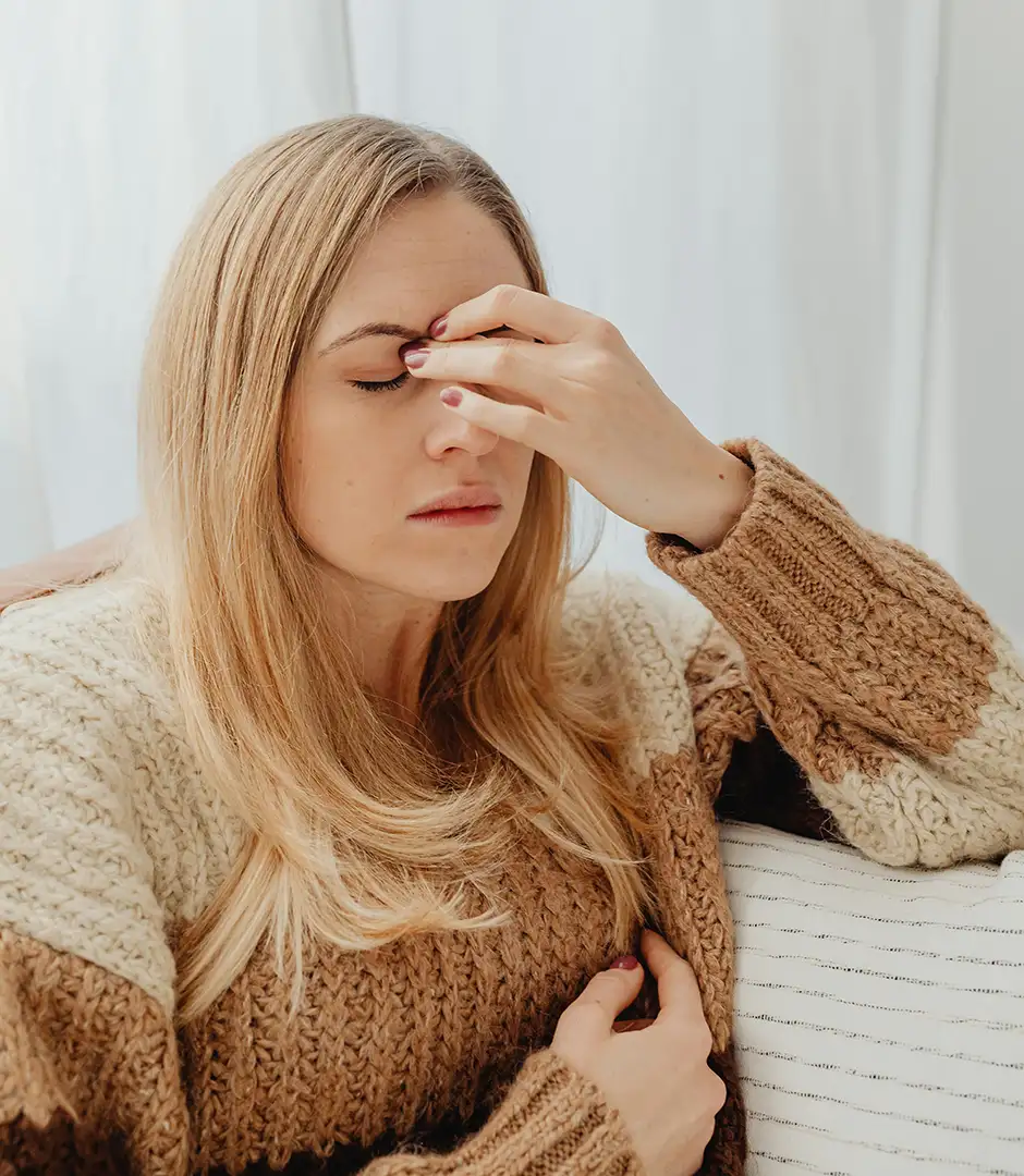 Woman with migraine/headache pinching nose and sinuses