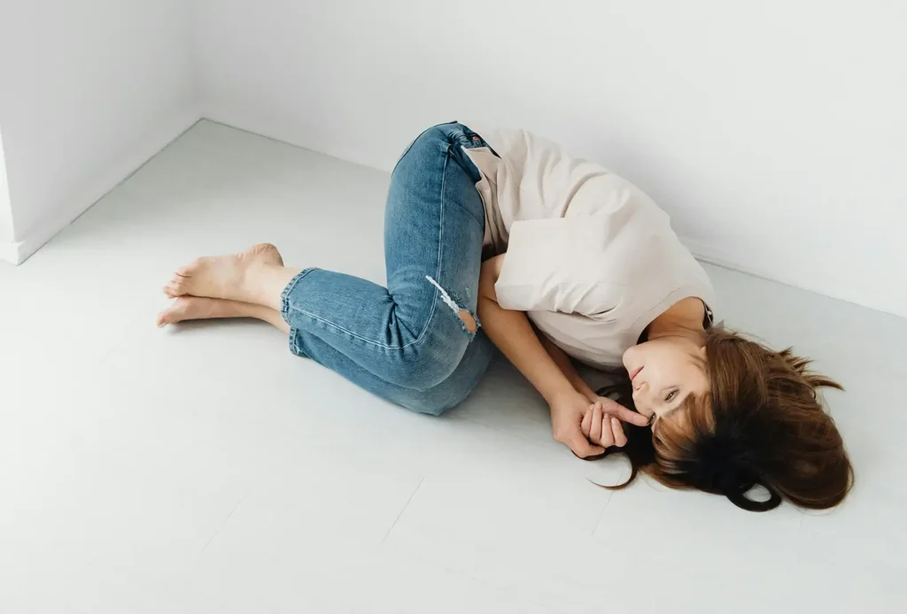 Woman with chronic pain laying down on floor