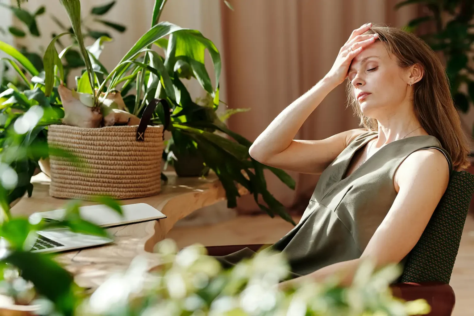 woman suffering from migraine and constant headaches while at work