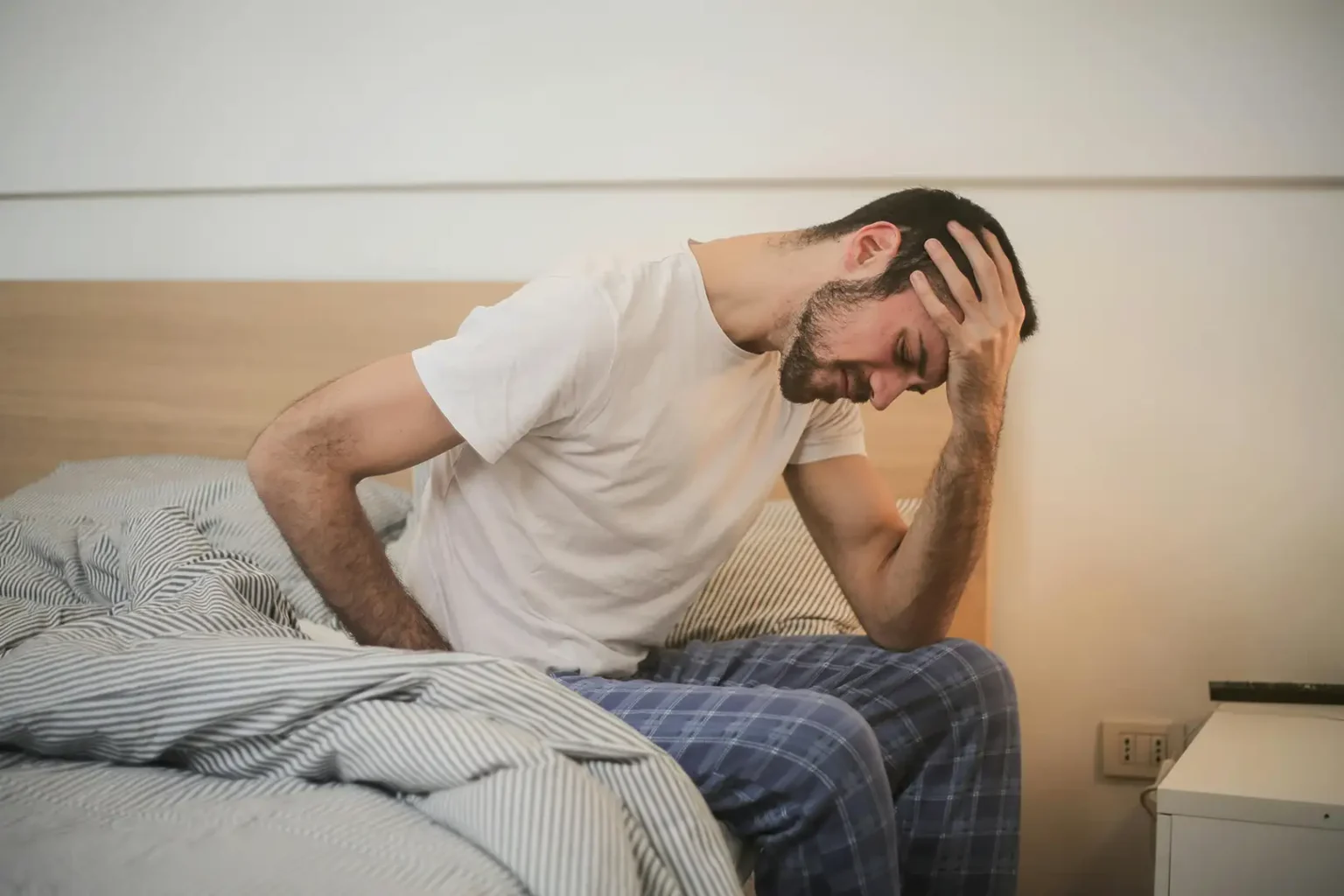 Fatigued man struggling to get out of bed.