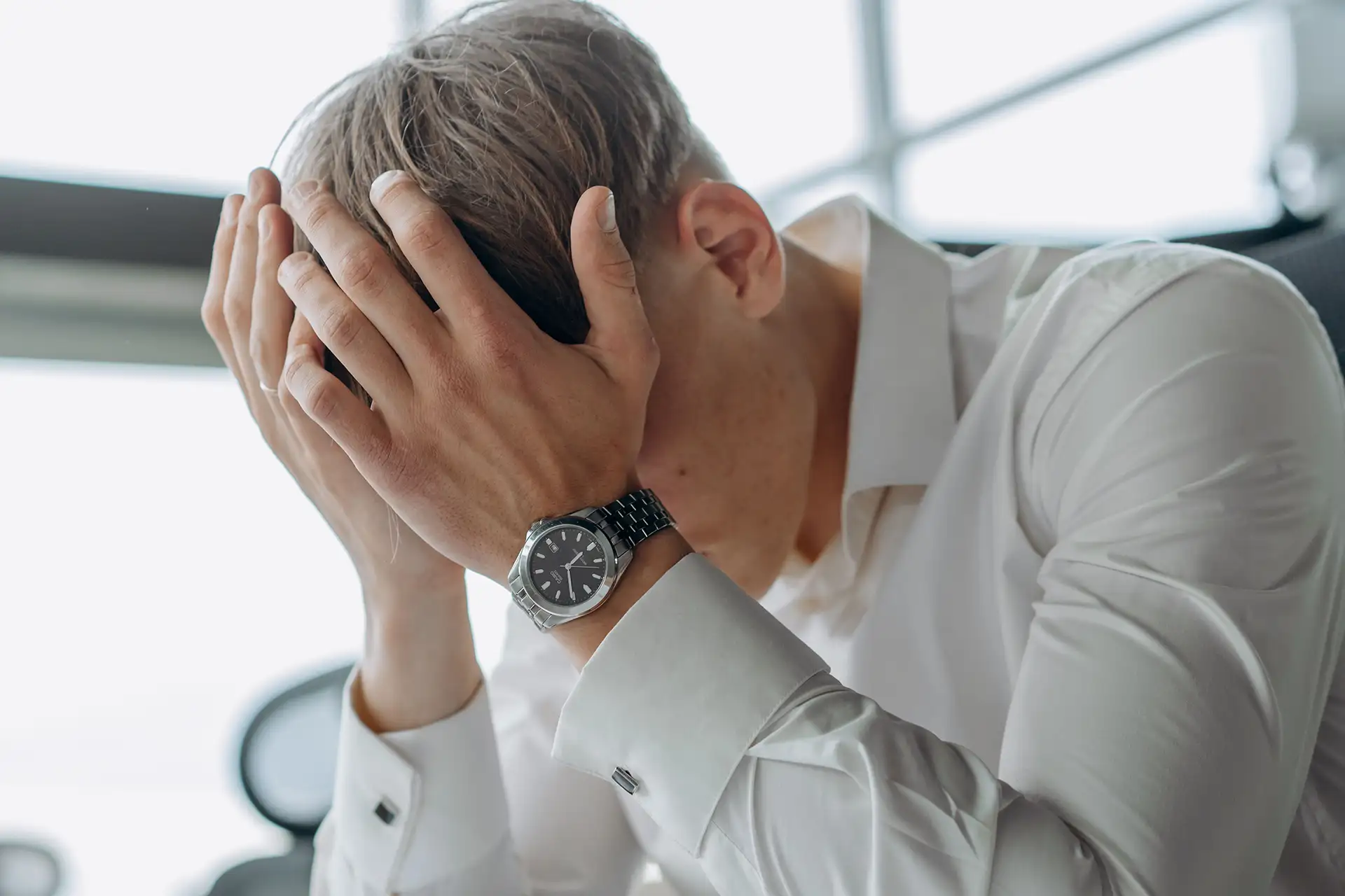 A business professional showing stress and fatigue with head in hands