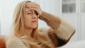 Woman suffering from vertigo and dizziness holding forehead