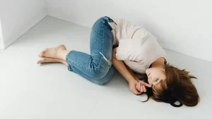 Woman with chronic pain laying down on floor