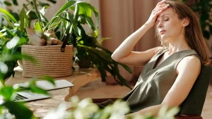 woman suffering from migraine and constant headaches while at work